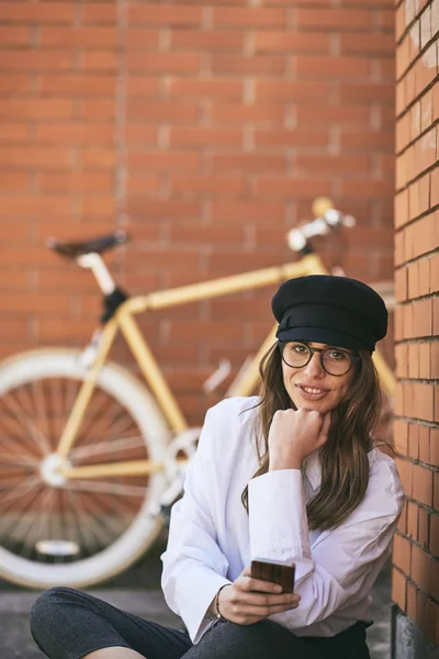 Жінка Сидить Тротуарі Використовує Смартфон Чорновому Жовтому Велосипеді — стокове фото