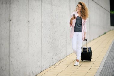 Bagaj taşıma ve karakola yürürken akıllı telefon kullanan kadın.