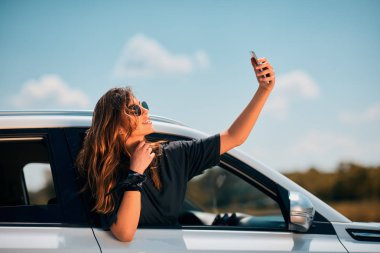 Selfie araba camına yaslanmış çekici kadın.