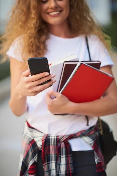 Estudiante Usando Teléfono Inteligente Sosteniendo Libros Mientras Camina Campus — Foto de Stock