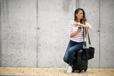 Bagaj üzerinde oturan ve akıllı telefon kullanan kadın.