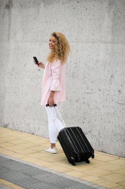 Bagaj taşıma ve karakola yürürken akıllı telefon kullanan kadın.