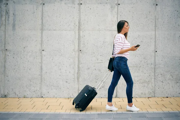 Mujer Que Lleva Equipaje Usa Teléfono Inteligente Mientras Camina Hasta — Foto de Stock