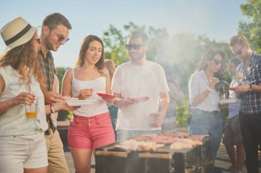 Bir grup insan mangal yapıyor, sohbet ediyor, içiyor ve yemek yiyor.. 