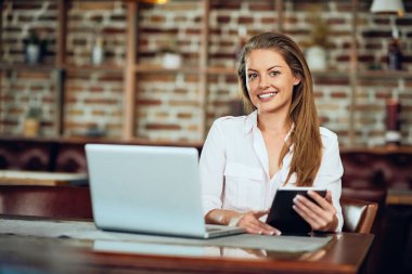Kafeteryada otururken tablet kullanarak iş kadını. Tablo laptop ve kahve.