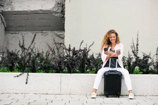 Viajero Femenino Usando Teléfono Inteligente Sosteniendo Café Mientras Está Sentado — Foto de Stock