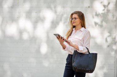 Açık havada duran ve tablet kullanarak iş kadını.