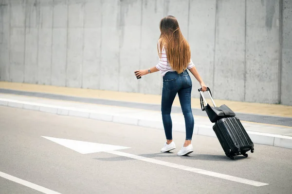 Woman carrying luggage while walking on the street.