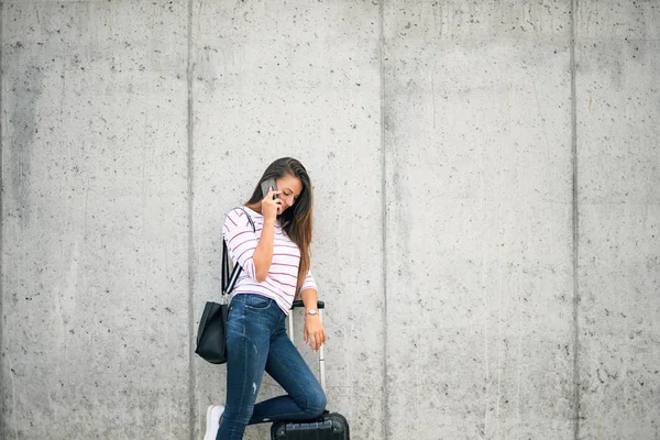 Kobieta Pomocą Inteligentnego Telefonu Jednocześnie Opierając Się Bagaż Ulicy — Zdjęcie stockowe