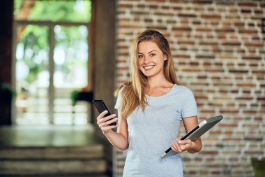Kafede dururken akıllı telefon kullanarak iş kadını. Dizüstü tutan diğer elinde.