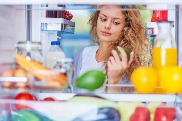 Женщина Берет Авокадо Холодильника Приготовить Завтрак Стоя Перед Открытым Холодильником — стоковое фото