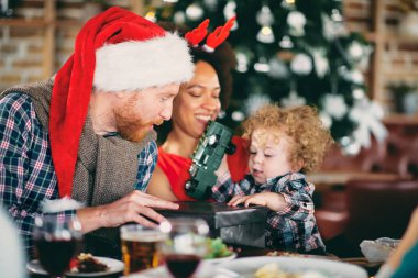 Masada otururken yürümeye başlayan çocuk için hediye vermek arkadaş. Noel ağacı içinde geçmiş. Noel tatil kavramı.