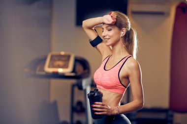 Spor salonunda duran ve içme suyu sportif kadın. Sağlıklı yaşam konsepti.