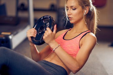 Sportif kadın ağırlık plaka ile egzersizi yapıyor. Spor salonu iç.