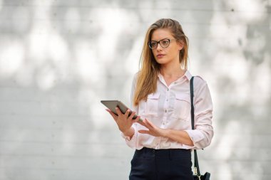 Açık havada duran ve tablet kullanarak iş kadını.