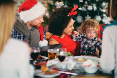 Yürümeye başlayan çocuk masasında otururken Noel hediye vererek karışık ırk kadın ve erkek. Noel tatil kavramı.