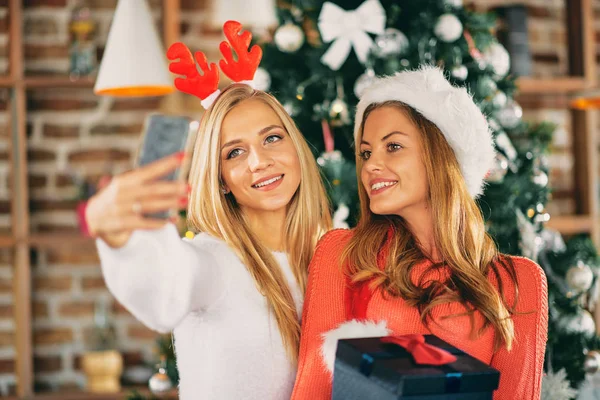 Girlfriends Taking Selfie Holding Gifts While Standing Front Christmas Tree — Stock Photo, Image