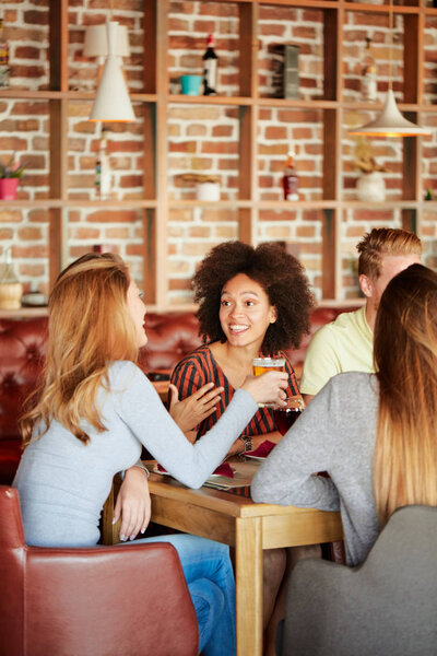 Group of friends having dinner at restaurant. Friends cheering and drinking alcohol.