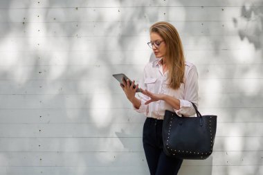 Açık havada duran ve tablet kullanarak iş kadını.
