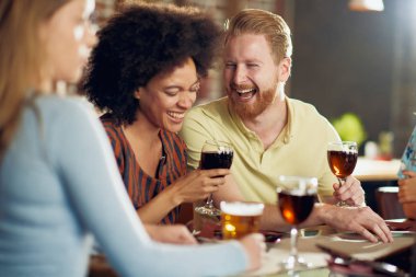 Restoranda oturan ve şarap ve bira içme Multicultiral arkadaşlar.