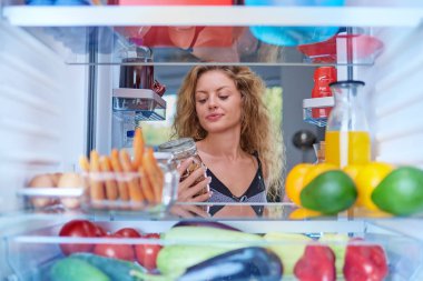 Kadın alarak kavanozdan buzdolabı yiyecek ato tam bir kahvaltı yapmak. Resim buzdolabının içinden çekilen.
