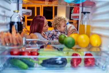 Anne ve oğlu buzdolabı süt alarak. Resim buzdolabının içinden çekilen.