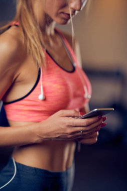 Akıllı telefon mesaj attığın için kullanarak / spor salonunda dururken çıkıyor kadının kapatın. Sağlıklı yaşam konsepti.