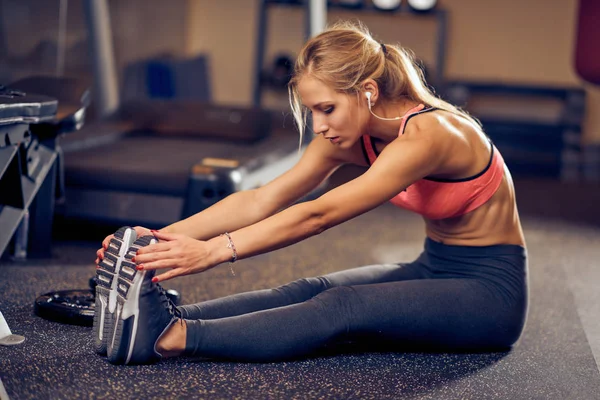 Kvinnan Sträcker Benen När Man Sitter Ett Gym Golv Bakgrunden — Stockfoto