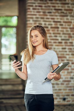 Kafede dururken akıllı telefon kullanarak iş kadını. Dizüstü tutan diğer elinde.