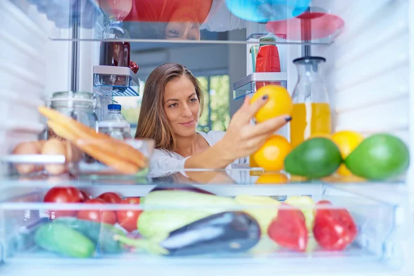 Женщина Стоящая Перед Открытым Холодильником Принимающая Апельсиновые Фрукты Холодильник Полный — стоковое фото