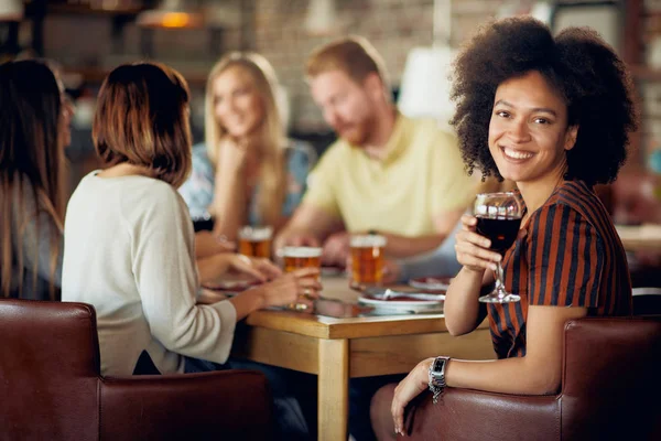 Žena Při Pohledu Fotoaparát Drží Sklenku Vína Při Posezení Restauraci — Stock fotografie