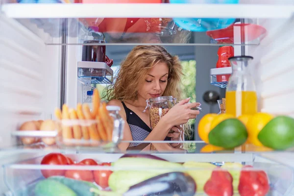 Mujer Oliendo Sosteniendo Frasco Abierto Mientras Está Pie Frente Nevera —  Fotos de Stock