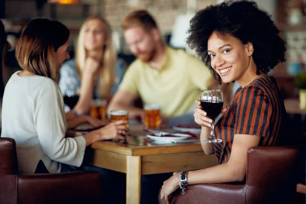 Žena Při Pohledu Fotoaparát Drží Sklenku Vína Při Posezení Restauraci — Stock fotografie