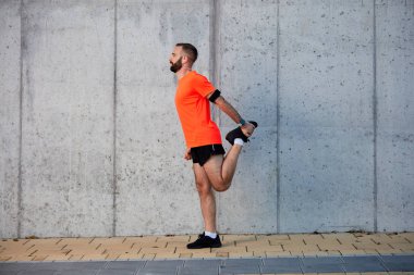 Sportif görünümünü yan sokakta çalıştırmadan önce bacaklar uzanan beyaz adam sakallı. Sağlıklı yaşam konsepti.