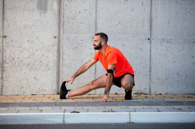 Sportif adam çalıştırmadan önce bacaklarını germe. Sağlıklı yaşam konsepti.