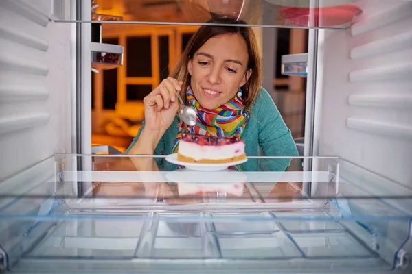 Frau Isst Torte Während Sie Vor Dem Kühlschrank Steht Bild — Stockfoto