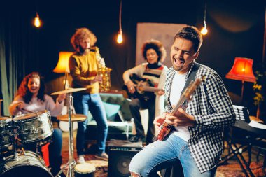 Şarkı ve ev stüdyosunda otururken bas gitar çalmaya dostum. İçinde kendi grubu aletleri oynamak arka plan.