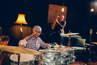 İki adam davul ve saksafon ev stüdyosunda oynarken.