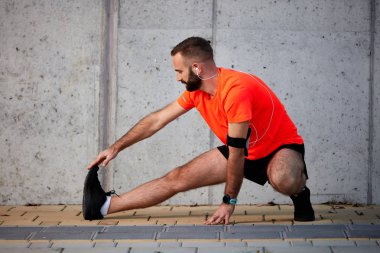 Sportif adam çalıştırmadan önce bacaklarını germe. Sağlıklı yaşam konsepti.