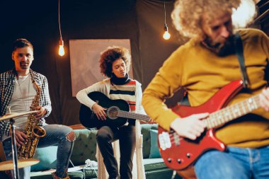 Bas gitarist sandalyede otururken gitar çalmak kapatın. Arka plan geri içinde. Ev stüdyosu iç.
