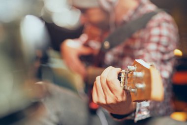 Genç müzisyen kulaklara kulaklık ile bas gitar çalmaya kapatın. Seçici odak üstünde el.