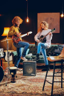 Cuaucasian kadın adam bas çalmaya akustik gitar çalmak. Ev stüdyosu iç.