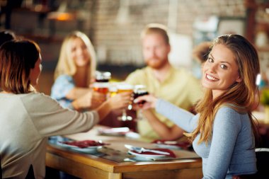 Kameraya bakarak ve kadeh kadeh şarap ile restoranda otururken yapma kadın.