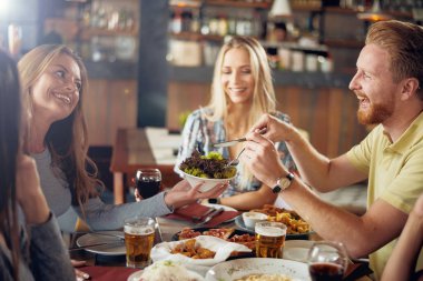 Restoranda akşam yemeği arkadaşlar. Kadın geçen salat adam için.
