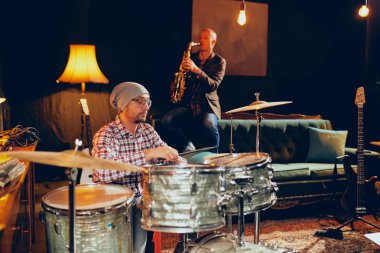 İki adam davul ve saksafon ev stüdyosunda oynarken.