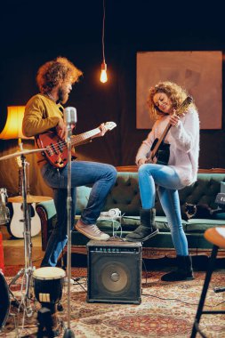 Akustik gitar bas çalmaya adam beyaz kadın. Ev stüdyosu iç.
