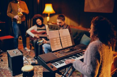 Woman playing clavier. Selective focus on woman. Home studio interior. clipart