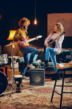 Akustik gitar bas çalmaya adam beyaz kadın. Ev stüdyosu iç.