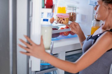 Kadın diyet cheesecake buzdolabı üzerinden alarak kırma. Dolap dolusu yiyecek.