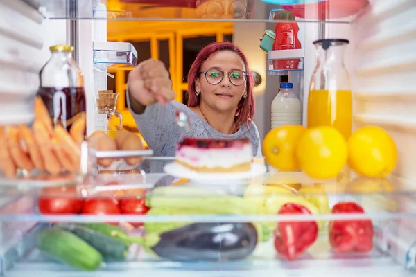 Женщина Стоящая Перед Холодильником Поедающая Торт Фотография Сделана Изнутри Холодильника — стоковое фото